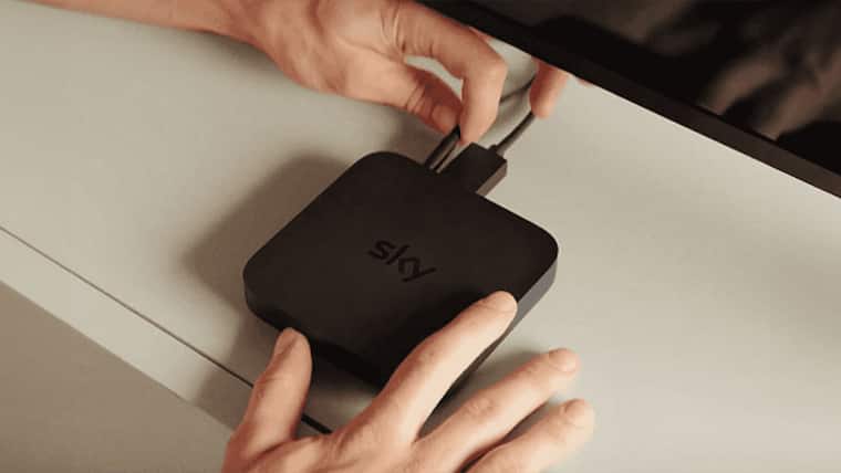 Zwei menschliche Hände verbinden eine Sky Stream Box mit dem Stromnetz-Kabel.